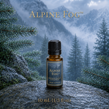 Alpine Fog™ perfume and cologne concentrate in an amber glass bottle with a blue-and-gold label, displayed against misty alpine mountains and wet silver fir branches - 10 ml