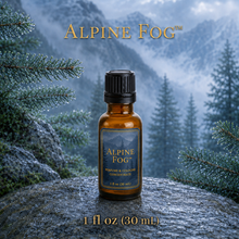 Alpine Fog™ perfume and cologne concentrate in an amber glass bottle with a blue-and-gold label, displayed against misty alpine mountains and wet silver fir branches - 1 oz