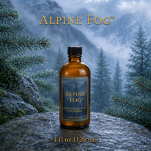 Alpine Fog™ perfume and cologne concentrate in an amber glass bottle with a blue-and-gold label, displayed against misty alpine mountains and wet silver fir branches - 4oz