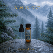 Alpine Fog™ perfume and cologne concentrate in an amber glass bottle with a blue-and-gold label, displayed against misty alpine mountains and wet silver fir branches - 3.7ml Dram