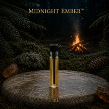 Midnight Ember™ perfume and cologne concentrate in an amber glass bottle with burgundy label beside a campfire in a dark evergreen forest -  1 ml vial