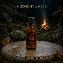 Midnight Ember™ perfume and cologne concentrate in an amber glass bottle with burgundy label beside a campfire in a dark evergreen forest -  1 fl oz