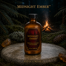 Midnight Ember™ perfume and cologne concentrate in an amber glass bottle with burgundy label beside a campfire in a dark evergreen forest -  8 fl oz 